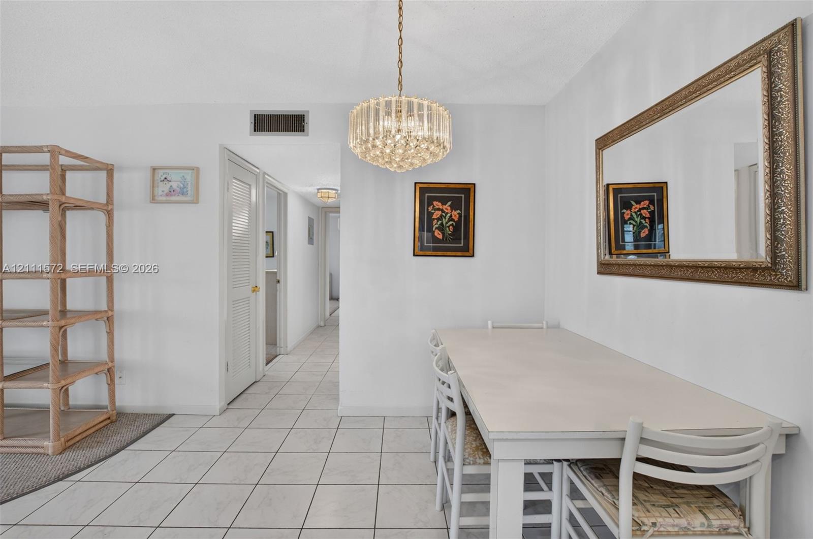 Dining area with neutral tile flooring and a multi-tiered crystal chandelier