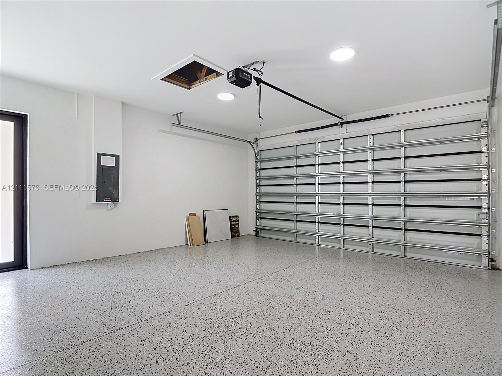 Garage space featuring an epoxy-coated floor, sectional garage door, recessed lighting, and direct-access exterior door