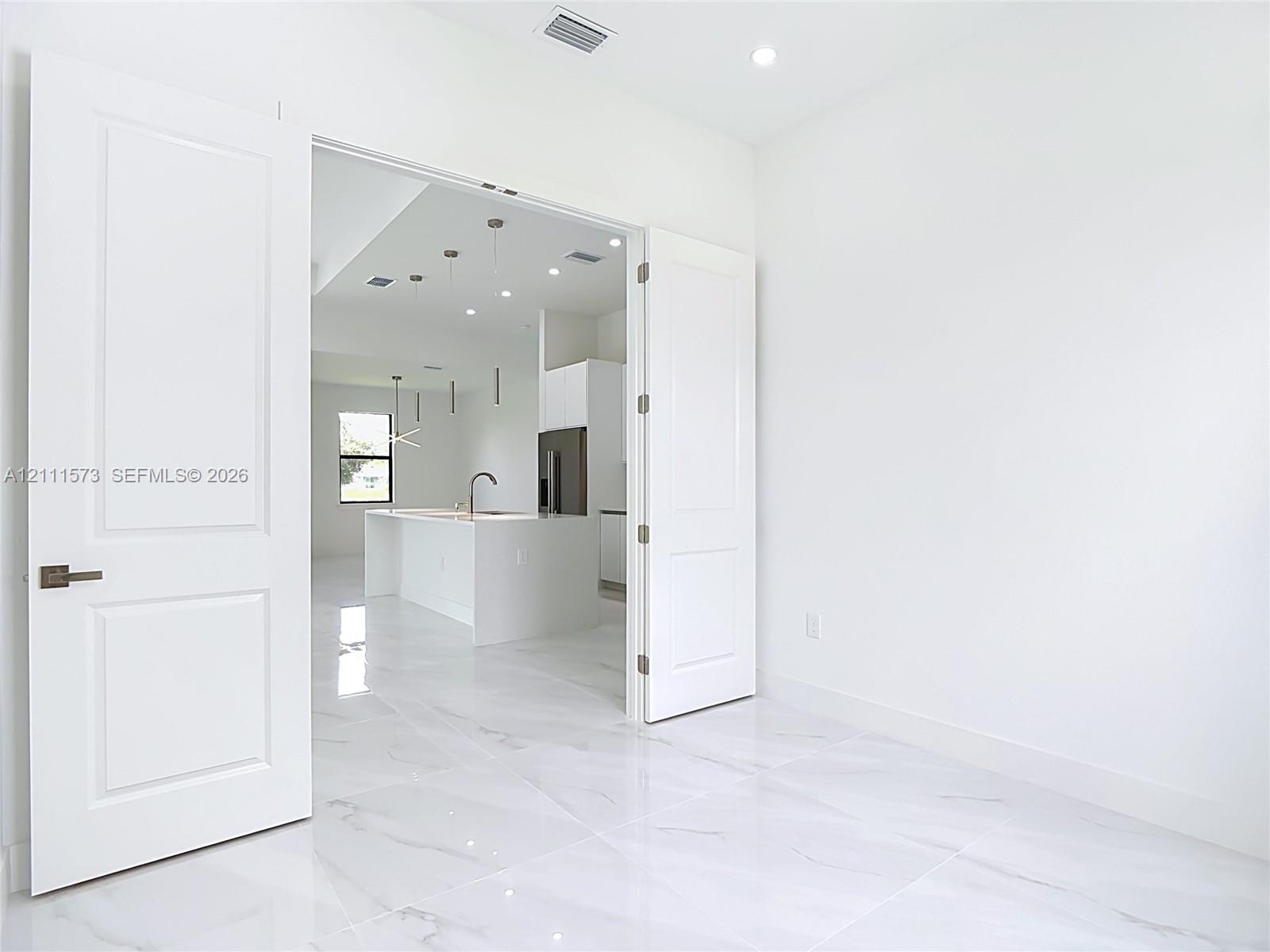 Interior space featuring large-format stone-finish tile flooring, white two-panel double doors with brushed nickel hardware, and recessed ceiling lighting