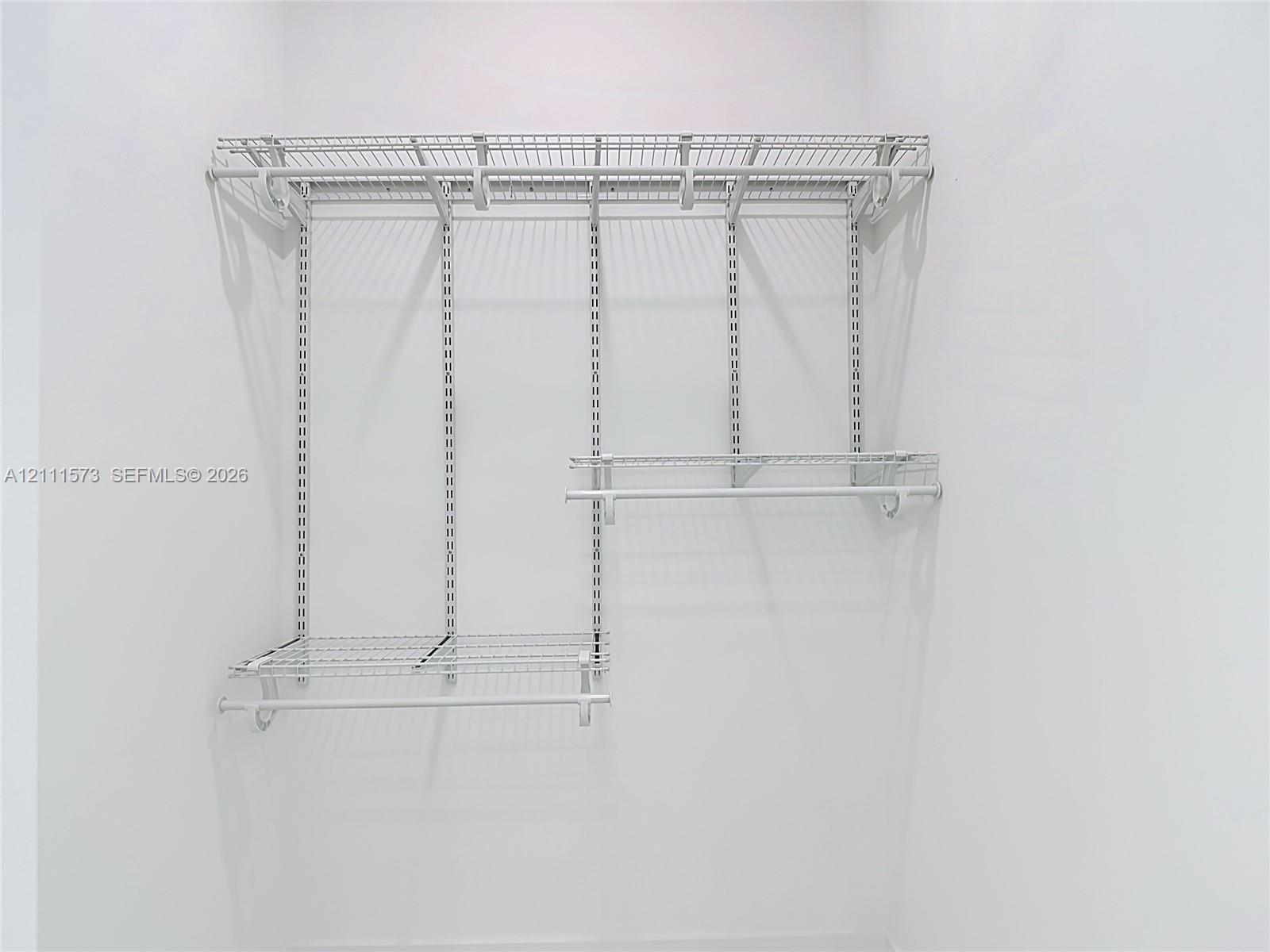 White wire shelving system featuring dual-tier hanging rods and adjustable track-mounted supports
