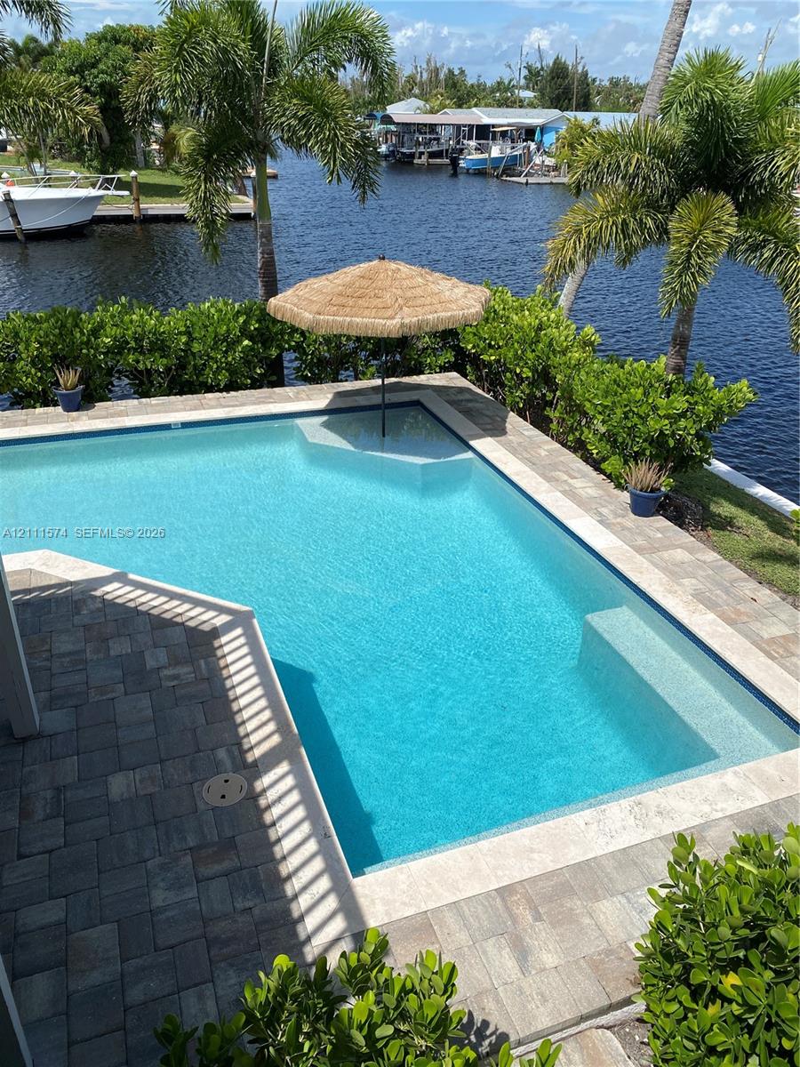 Waterfront swimming pool with paver decking and integrated step entry