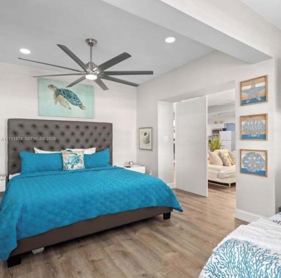 Multi-blade stainless steel ceiling fan with integrated lighting, wood-finish flooring, recessed ceiling lighting, and a neutral color palette