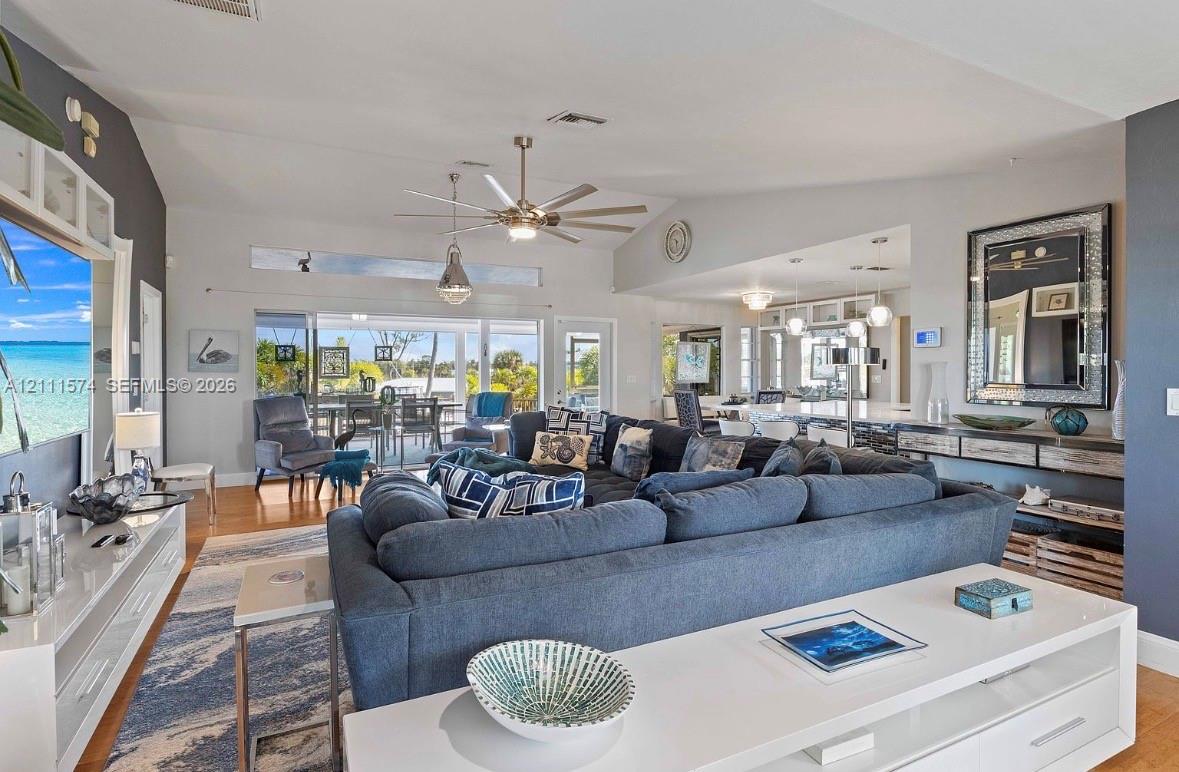 Open-concept living area featuring vaulted ceilings, recessed lighting, a modern ceiling fan, and large sliding glass doors leading to a covered patio