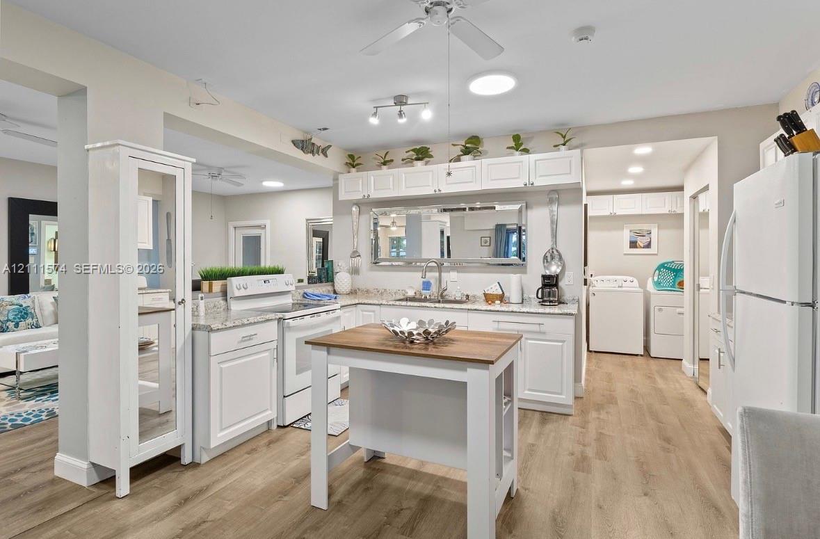 Kitchen featuring white shaker-style cabinetry, stone-finish countertops, wood-finish flooring, a portable kitchen island, and recessed lighting