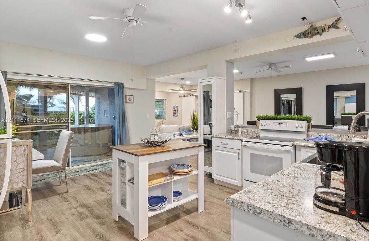 Kitchen featuring white cabinetry, stone-finish countertops, wood-finish flooring, a mobile kitchen island, and a sliding glass door