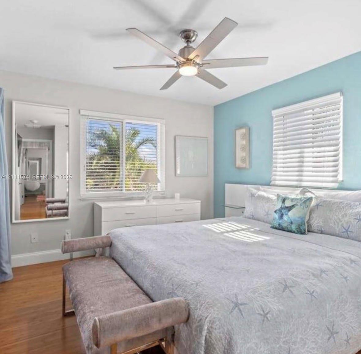 Brushed nickel ceiling fan with integrated lighting, wood-finish flooring, accent wall, and horizontal window blinds