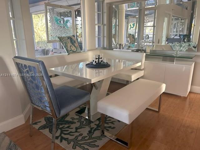 Built-in white storage cabinetry with a glass countertop, mirrored wall paneling, large-format windows, and wood-finish flooring