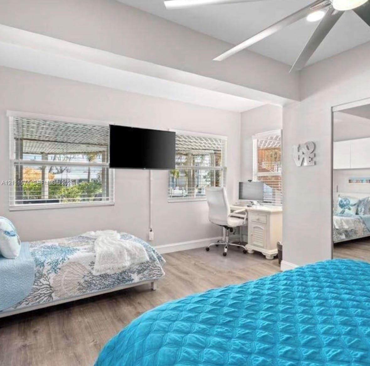 Room featuring a tray ceiling, recessed lighting, wood-finish flooring, and mirrored closet doors