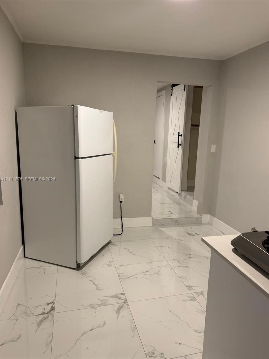 Large-format white stone-patterned tile flooring, white sliding barn-style door with dark hardware, and clean neutral wall finishes