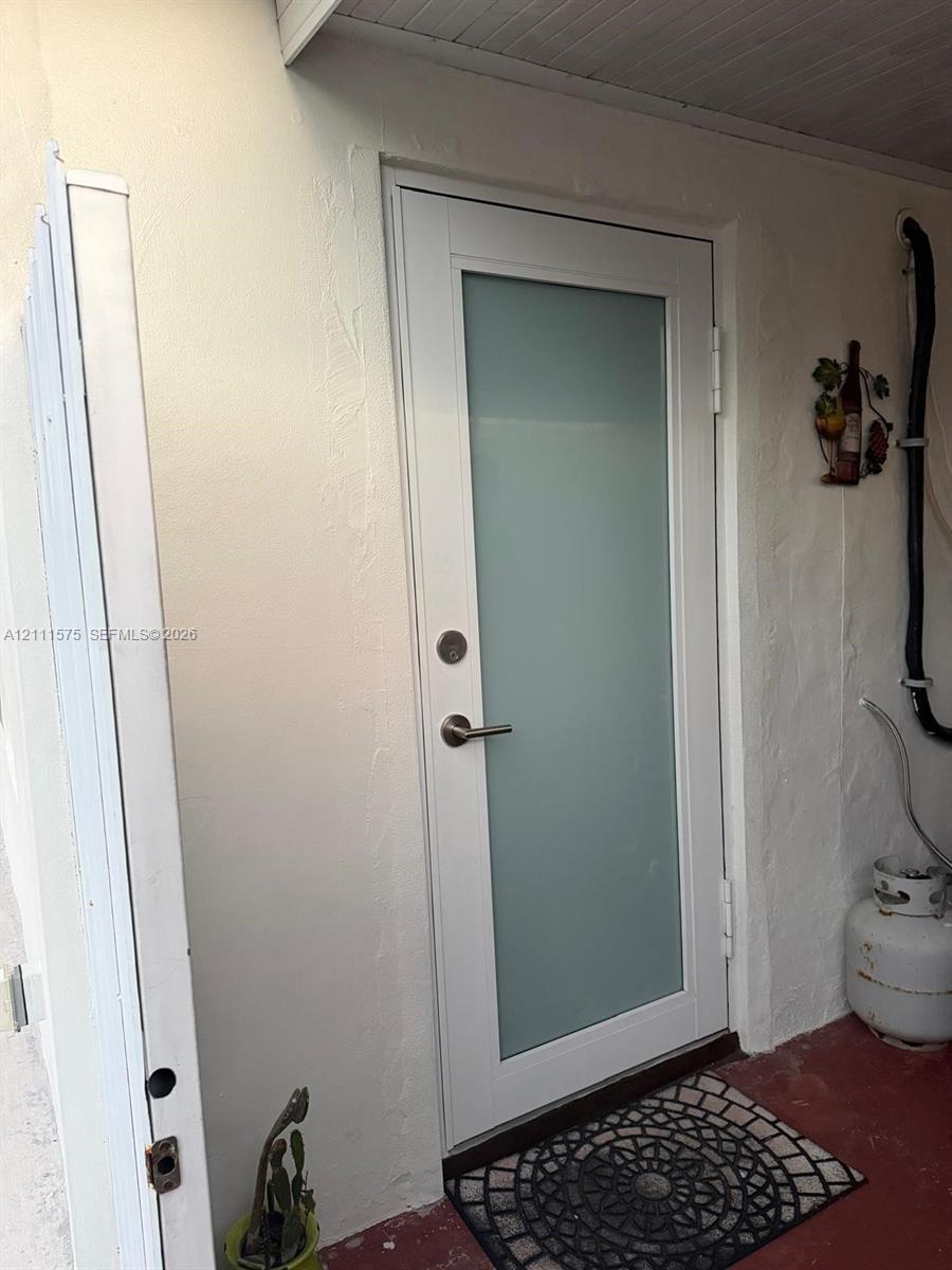 White exterior door featuring a central frosted glass pane, metallic lever handle, and a deadbolt lock