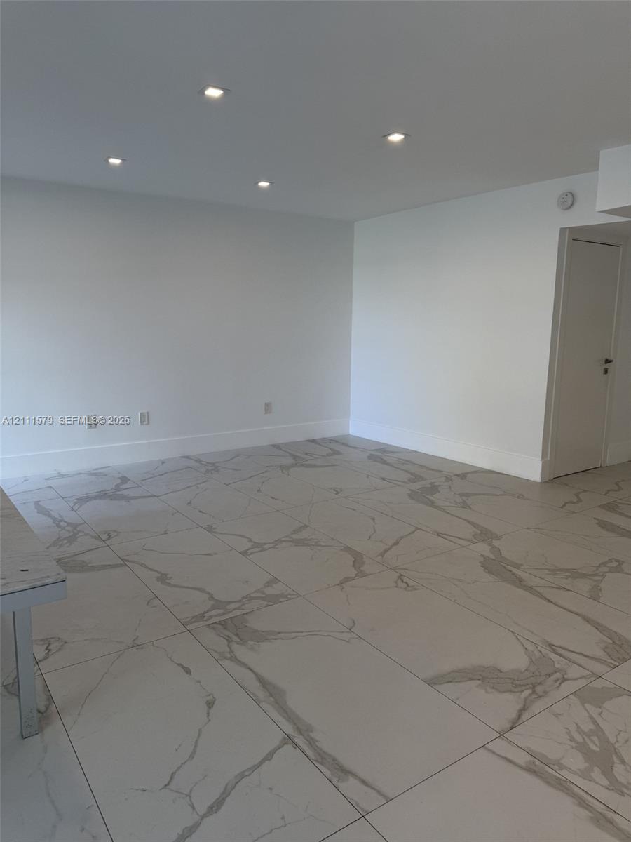 Neutral-toned large-format tile flooring with marble-pattern veining, complemented by recessed ceiling lighting