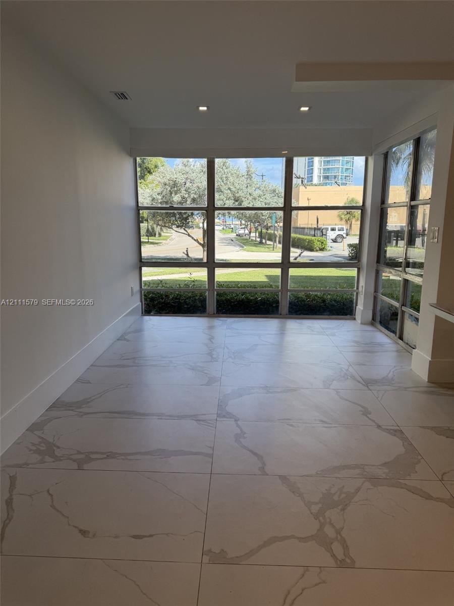 Floor-to-ceiling multi-pane windows, large-format stone-patterned tile flooring, and recessed ceiling lighting