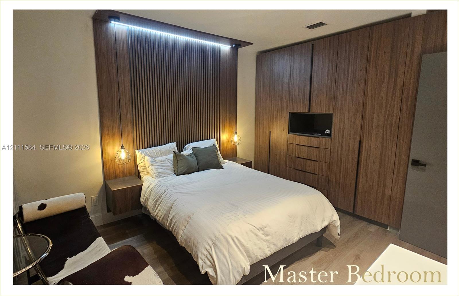 Wood-slat accent wall with integrated LED lighting, built-in floor-to-ceiling cabinetry, floating bedside tables, and wood-finish flooring