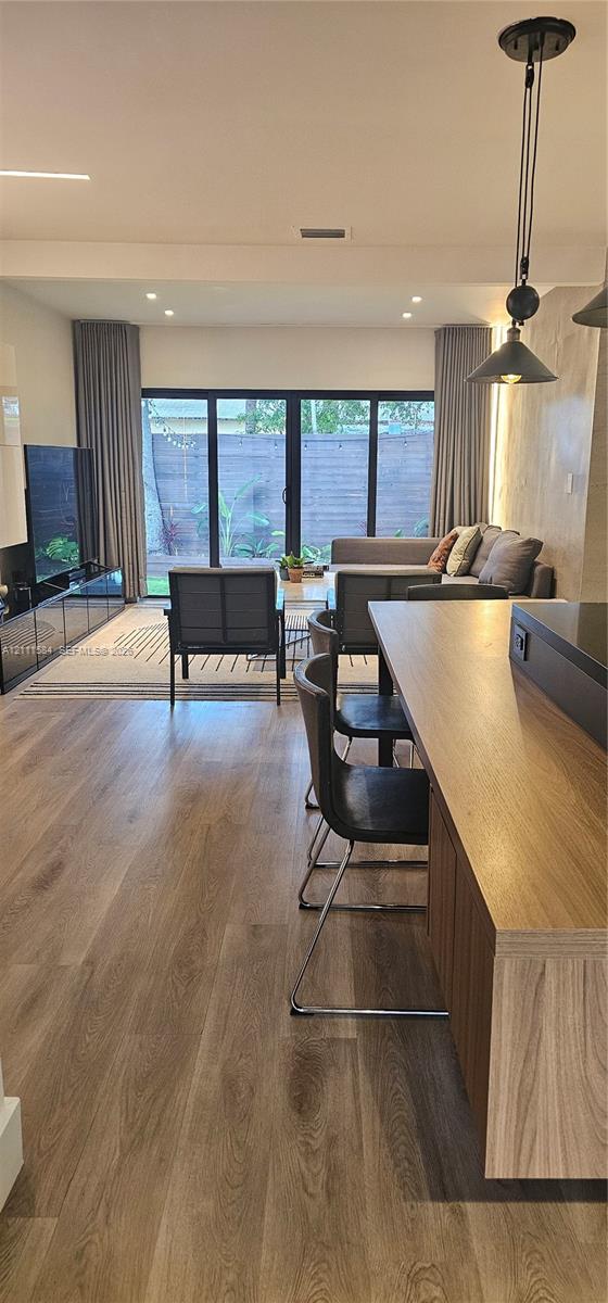 Open-concept interior featuring wood-finish flooring, recessed lighting, a built-in kitchen island, and multi-panel glass doors leading to the exterior