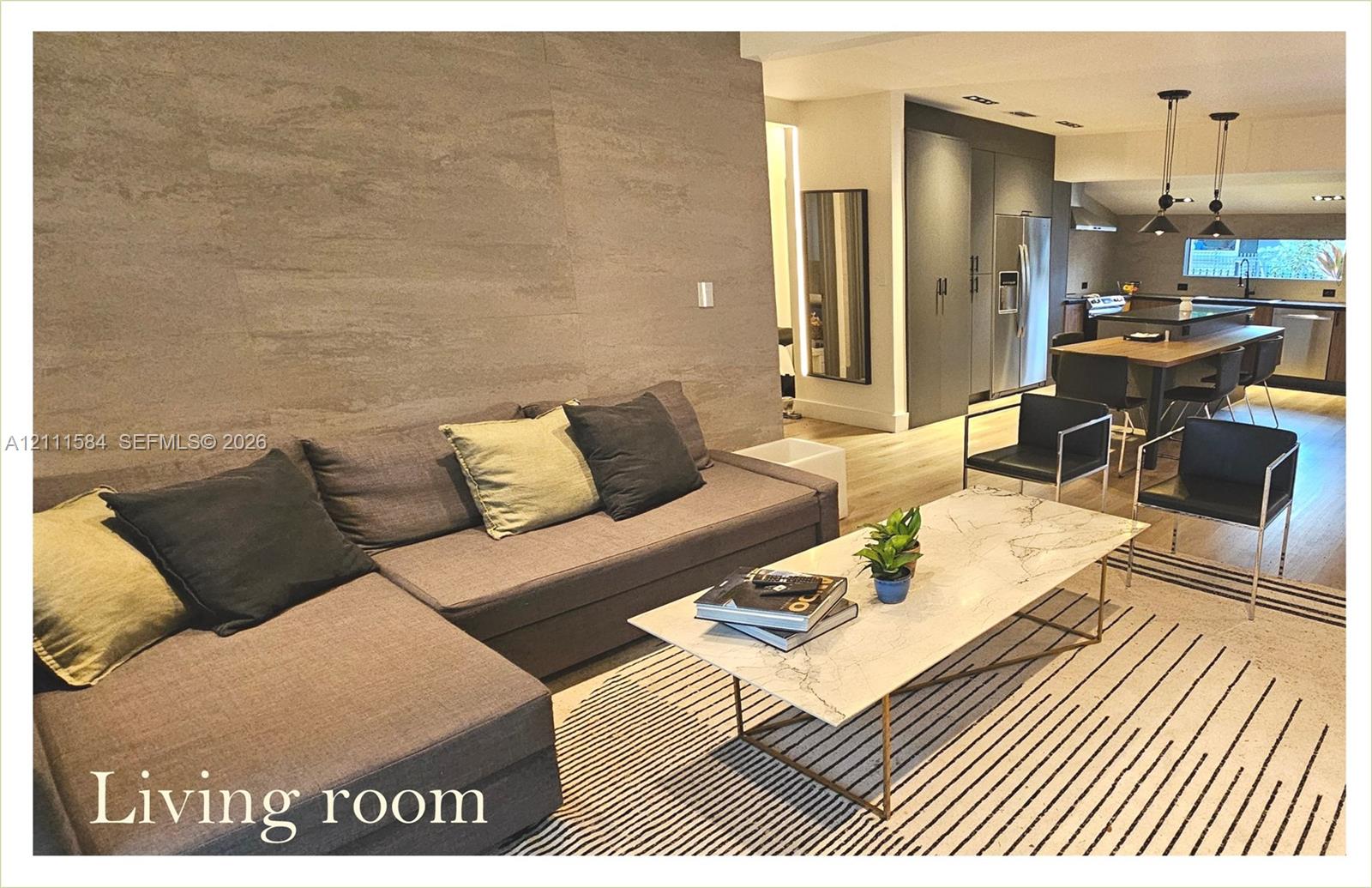 Textured accent wall featuring neutral tones, light wood-finish flooring, recessed lighting, and kitchen cabinetry with integrated appliances