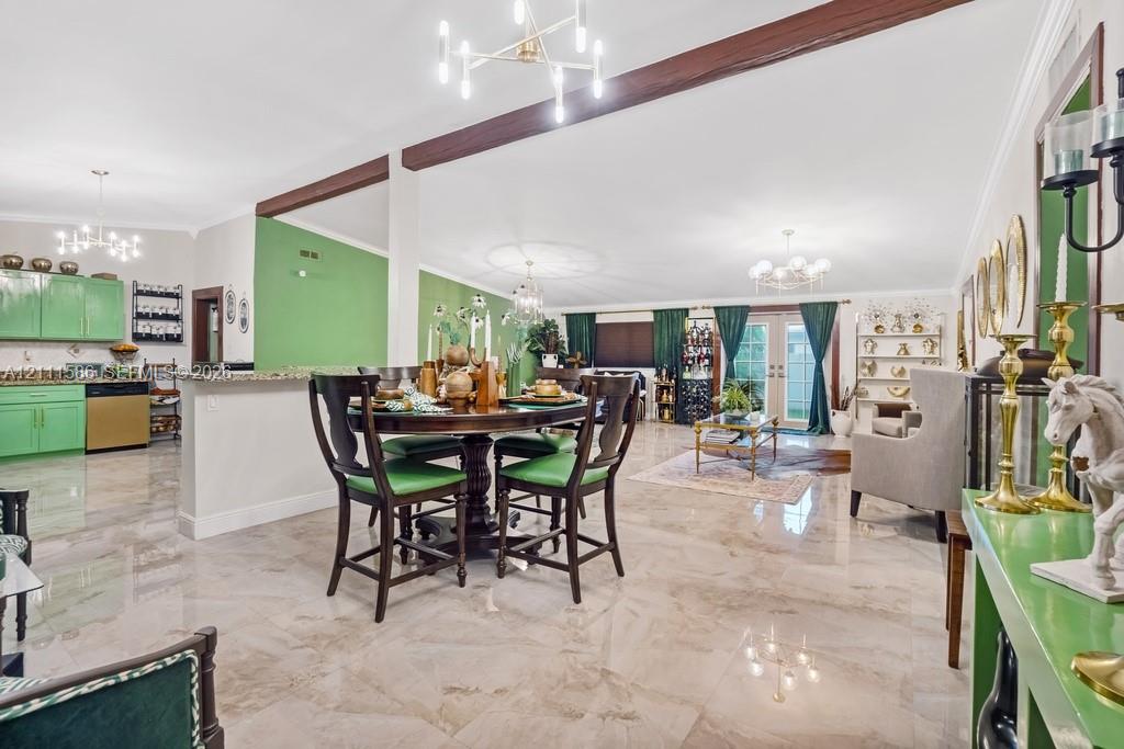 Open-concept interior featuring large-format tile flooring, exposed wood ceiling beams, a multi-arm modern chandelier, and glass-paned double doors