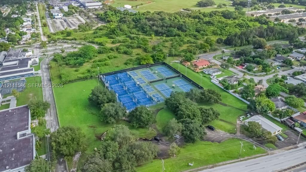 Multi-court tennis facility featuring fenced perimeters, high-mast sports lighting, and manicured green space