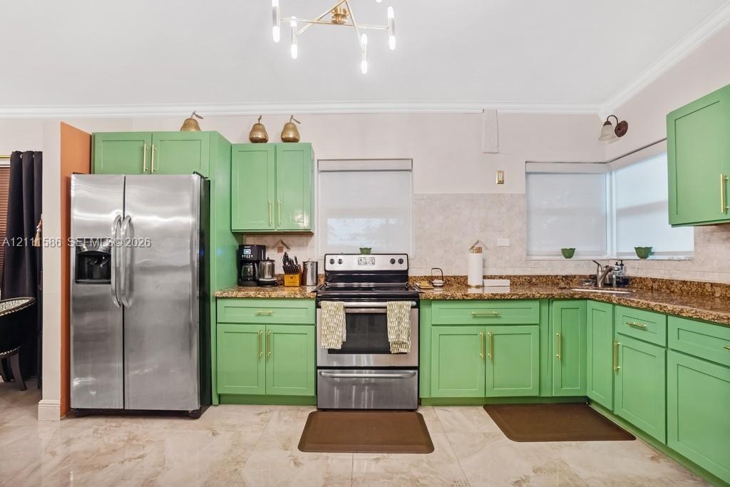 Kitchen featuring green shaker-style cabinetry, gold-tone hardware, stone-finish countertops, tile flooring, and a multi-arm geometric light fixture