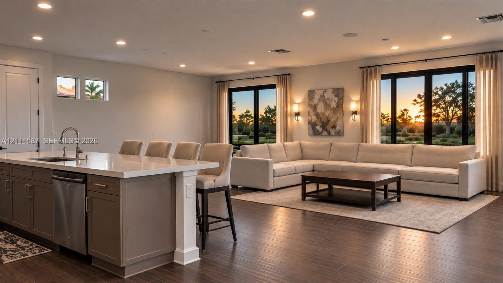 Open-concept living space featuring wood-finish flooring, recessed lighting, expansive windows with dark frames, and a kitchen island topped with a white solid-surface countertop