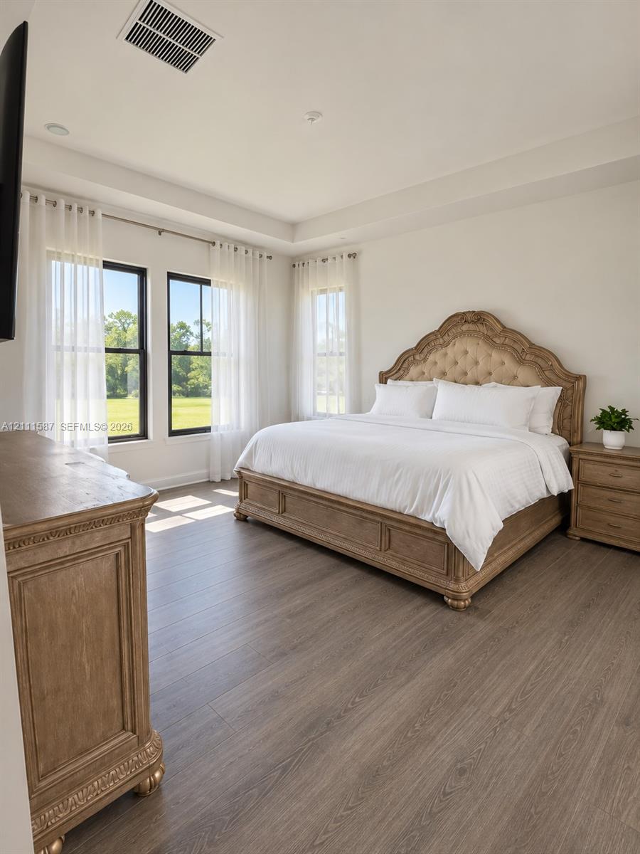 Tray ceiling, wood-finish flooring, and black-framed windows providing natural light