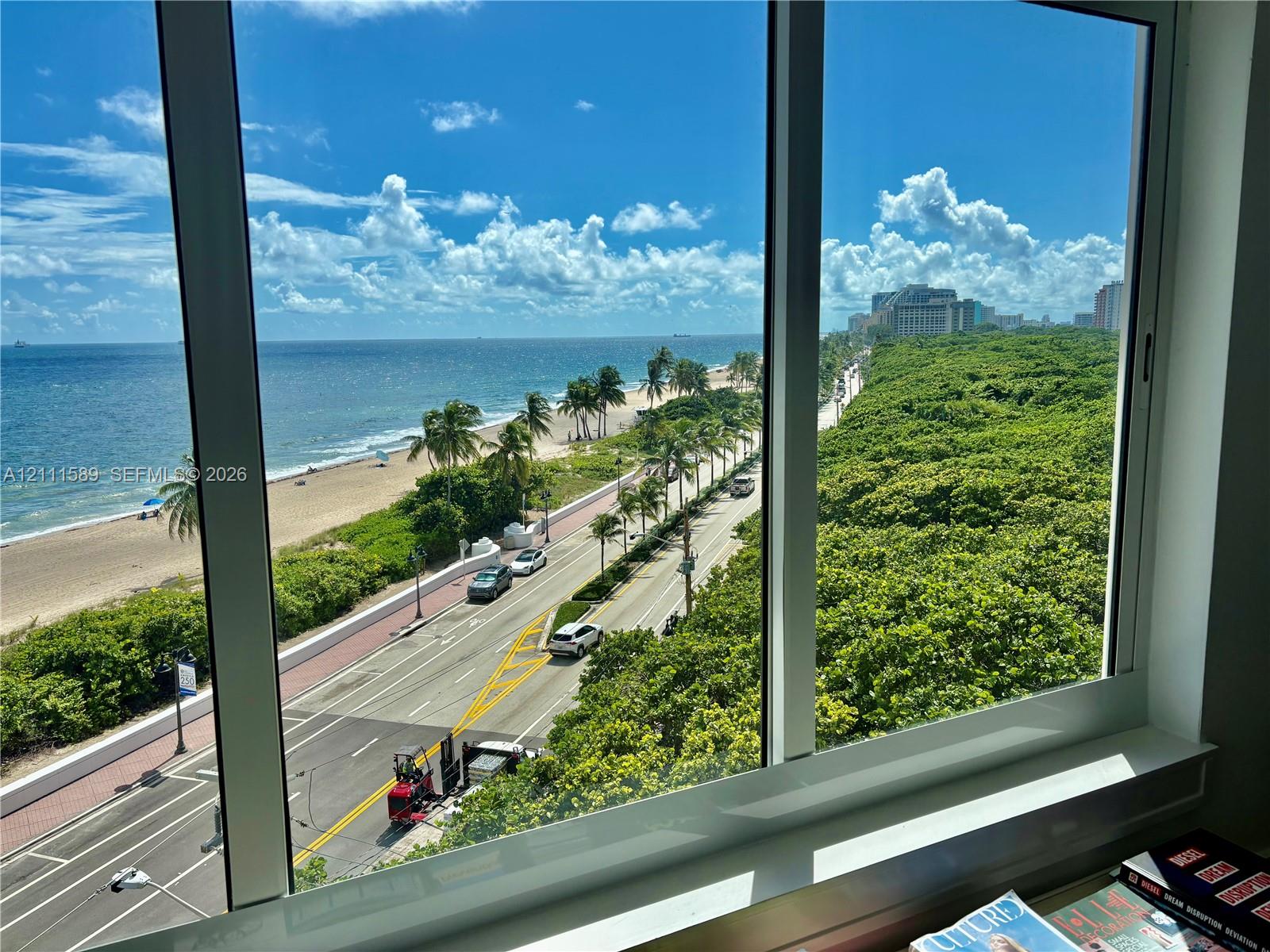 Floor-to-ceiling windows with coastal horizon, oceanfront scenery, and overhead exposure of established tree canopy and thoroughfare