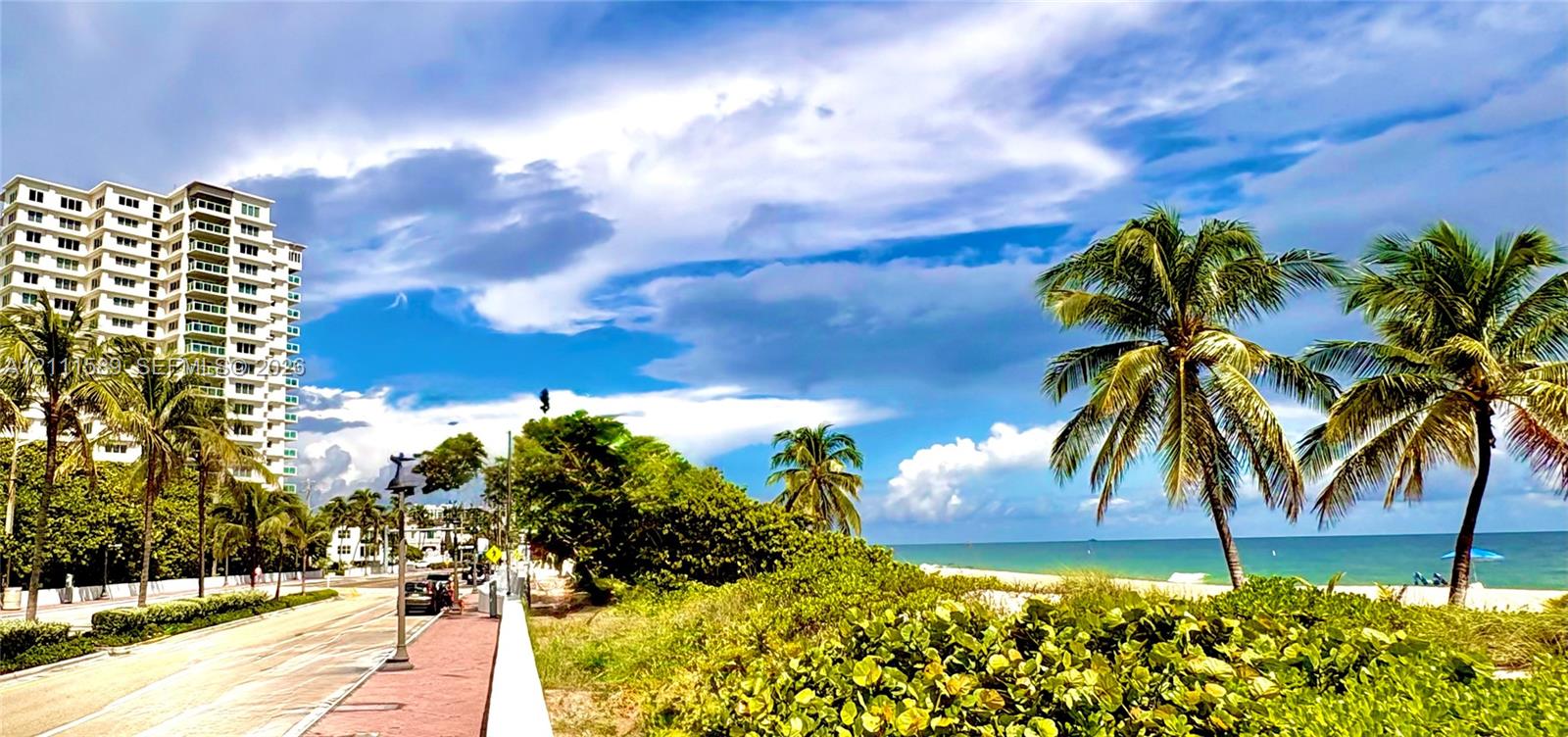 High-rise exterior featuring coastal scenery, palm trees, and direct proximity to the beach