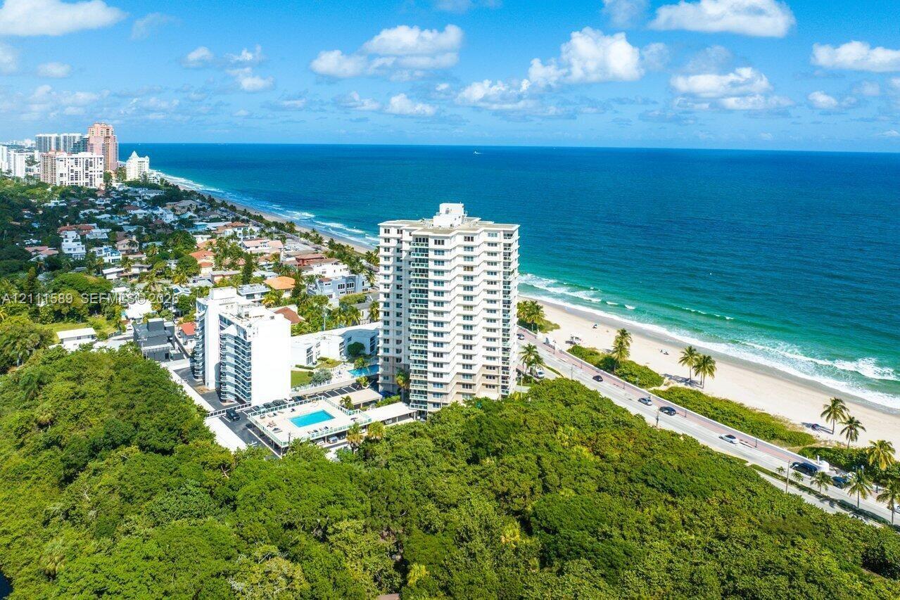 High-rise coastal residential building featuring private swimming pool, surrounding green space, and proximity to the shoreline High-rise coastal residential building featuring private swimming pool, surrounding green space, and proximity to the shoreline