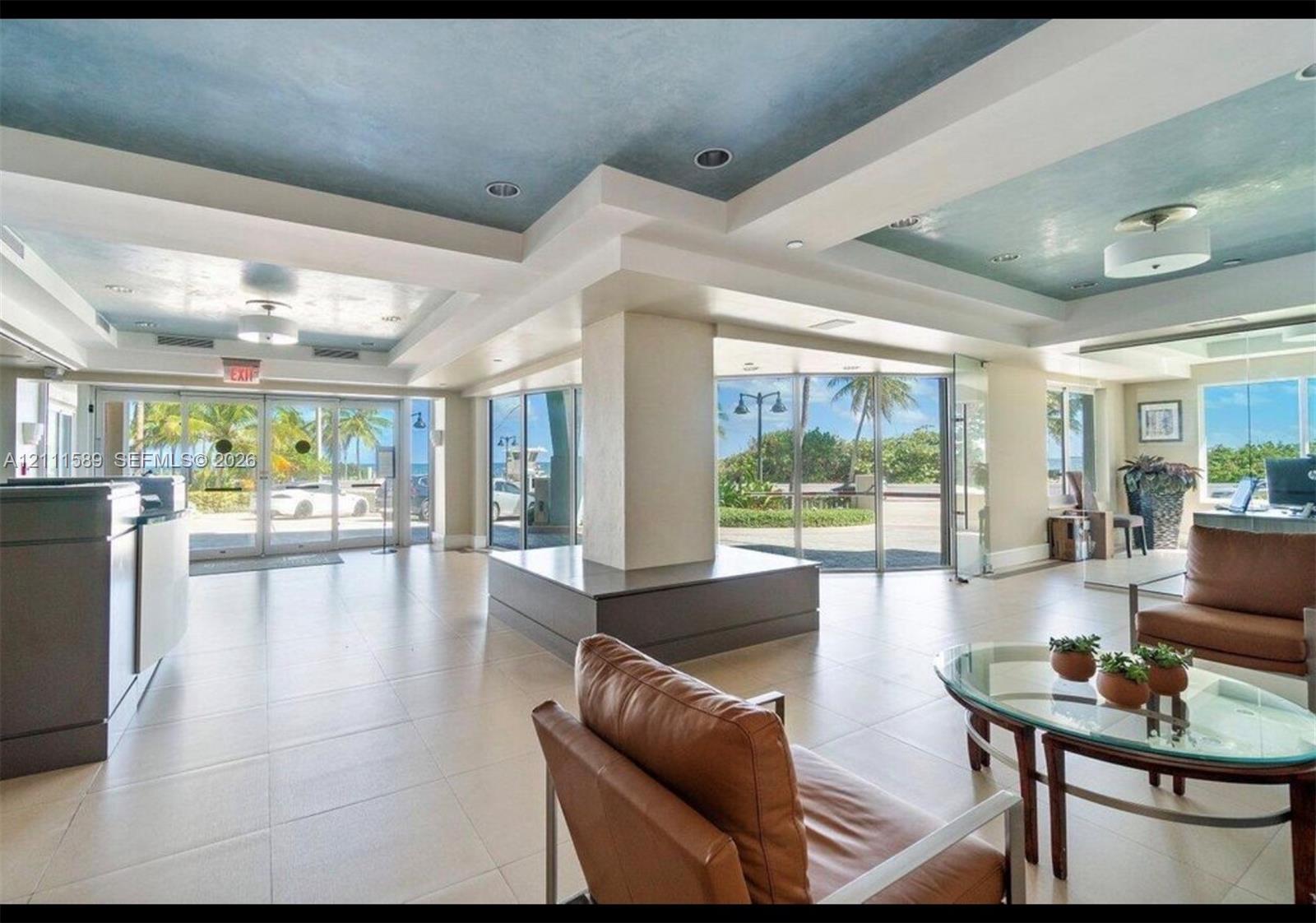 Lobby area featuring large-format tile flooring, recessed ceiling lighting, a textured blue ceiling finish, and expansive floor-to-ceiling glass paneling Lobby area featuring large-format tile flooring, recessed ceiling lighting, a textured blue ceiling finish, and expansive floor-to-ceiling glass paneling