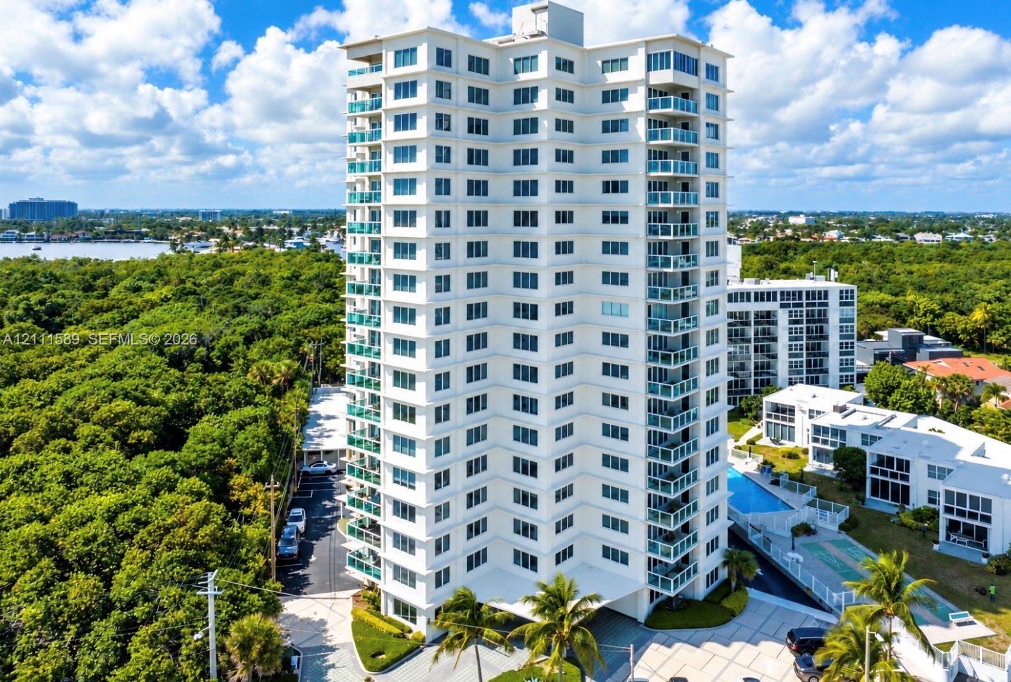 High-rise residential tower featuring private balconies, an exterior swimming pool, multi-level structural design, and paved surface parking High-rise residential tower featuring private balconies, an exterior swimming pool, multi-level structural design, and paved surface parking