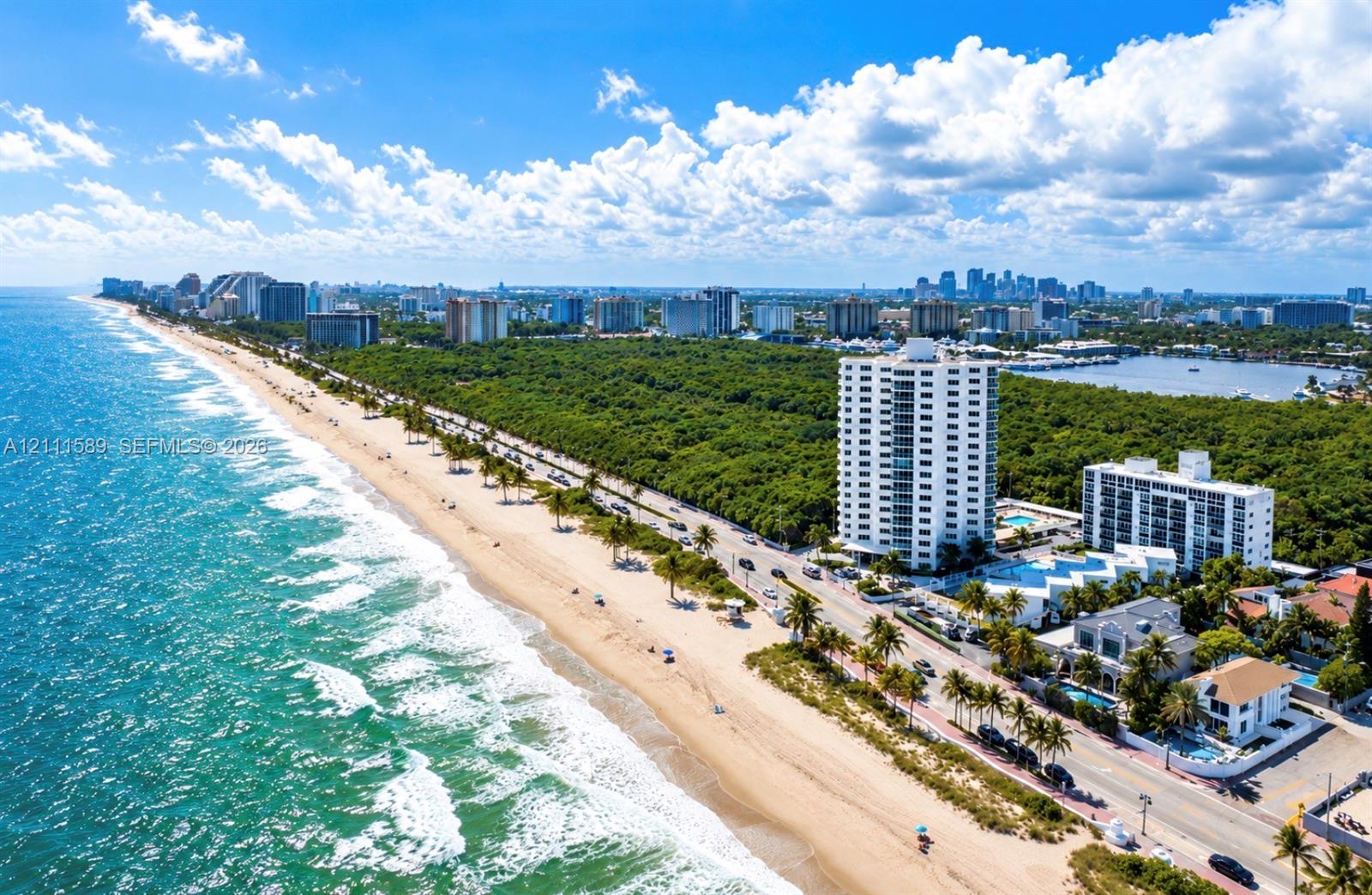 Coastal aerial perspective featuring direct oceanfront access, sandy shoreline, multi-story residential structures, lush tropical vegetation, and distant cityscape Coastal aerial perspective featuring direct oceanfront access, sandy shoreline, multi-story residential structures, lush tropical vegetation, and distant cityscape