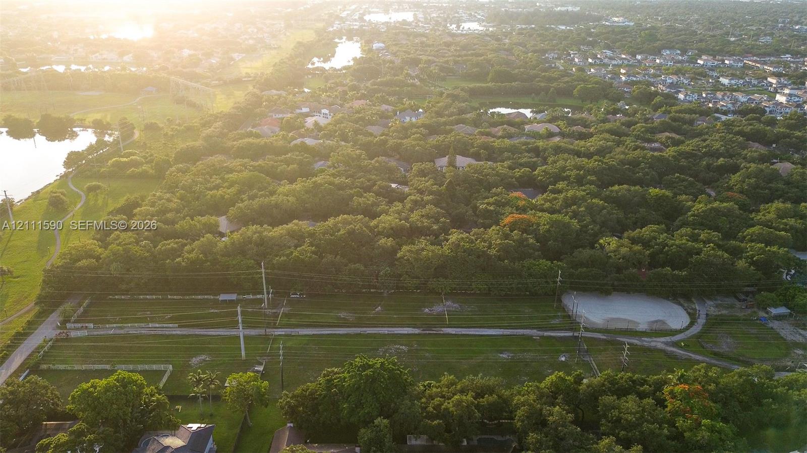 Aerial perspective of a sprawling parcel featuring expansive green space, mature tree canopy, and established landscaping