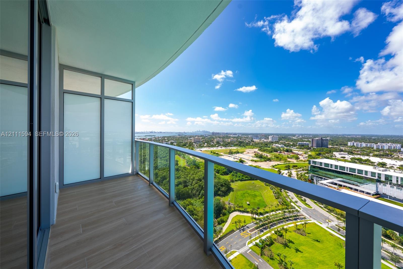 Covered balcony featuring wood-finish flooring, glass panel railings, and full-height exterior windows