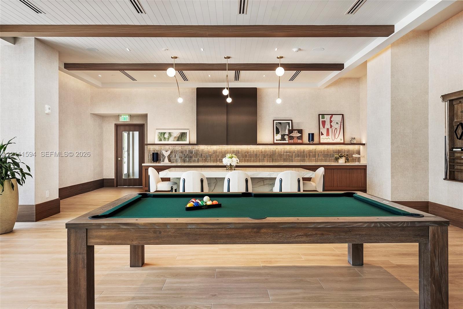Wood-finish flooring, exposed ceiling beams, stone-top island with integrated cabinetry, tile backsplash, and recessed lighting