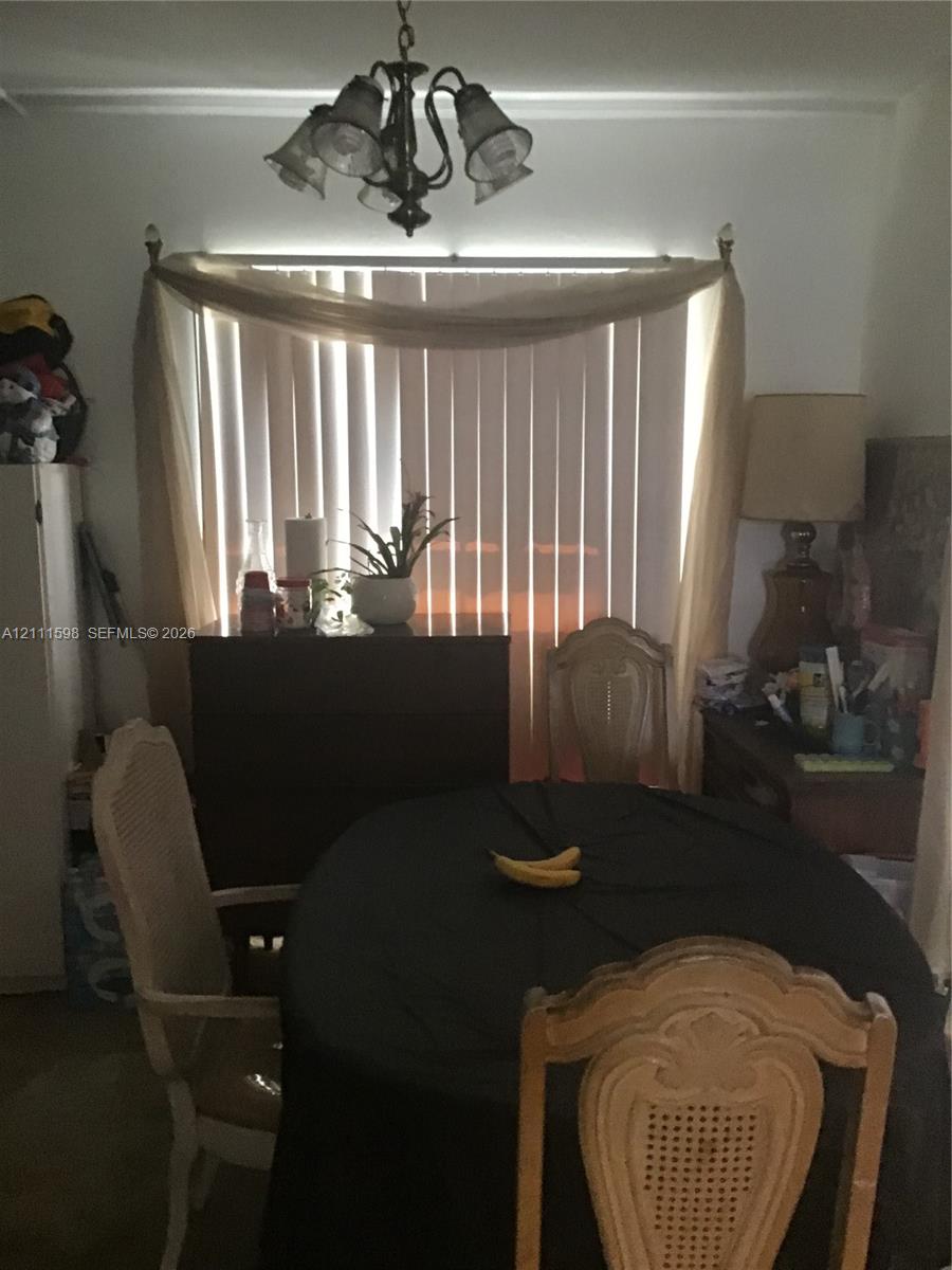 Large window with vertical blinds and a multi-arm, bronze-finish overhead light fixture Large window with vertical blinds and a multi-arm, bronze-finish overhead light fixture