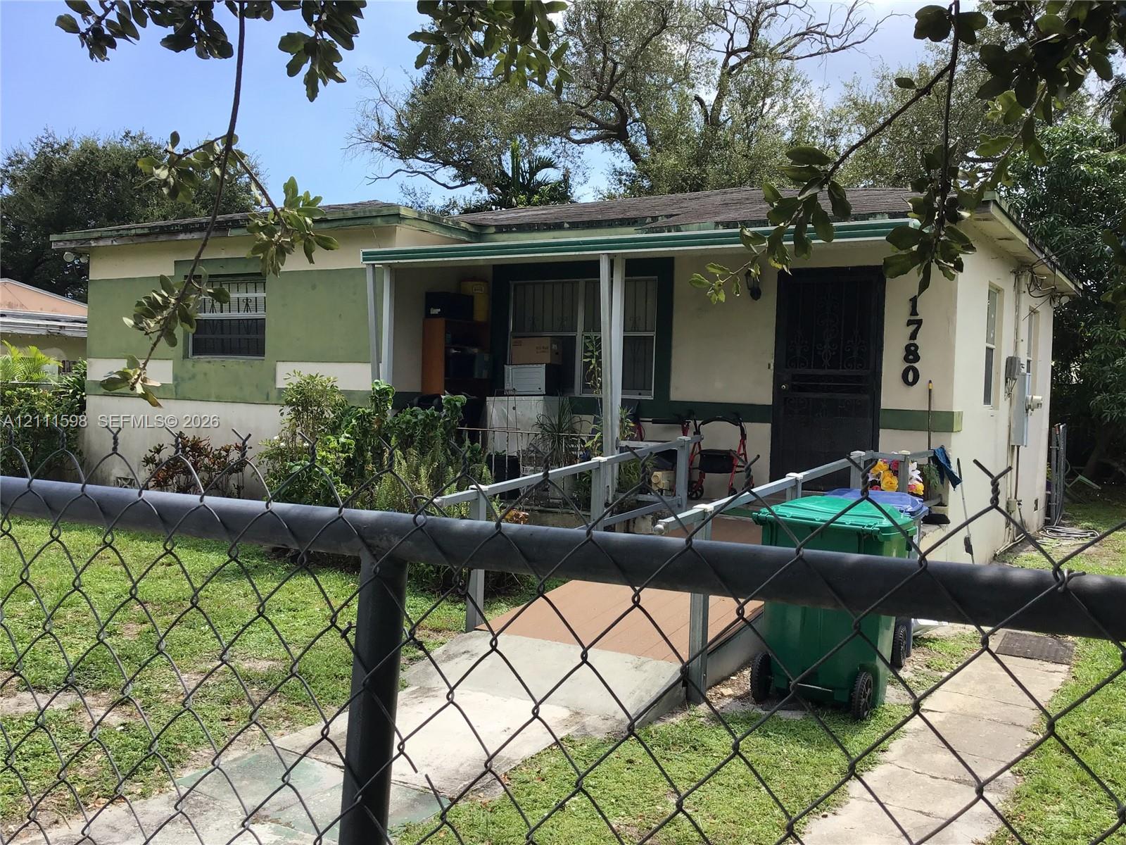 Single-story exterior featuring a front porch with a metal access ramp and chain-link fencing Single-story exterior featuring a front porch with a metal access ramp and chain-link fencing
