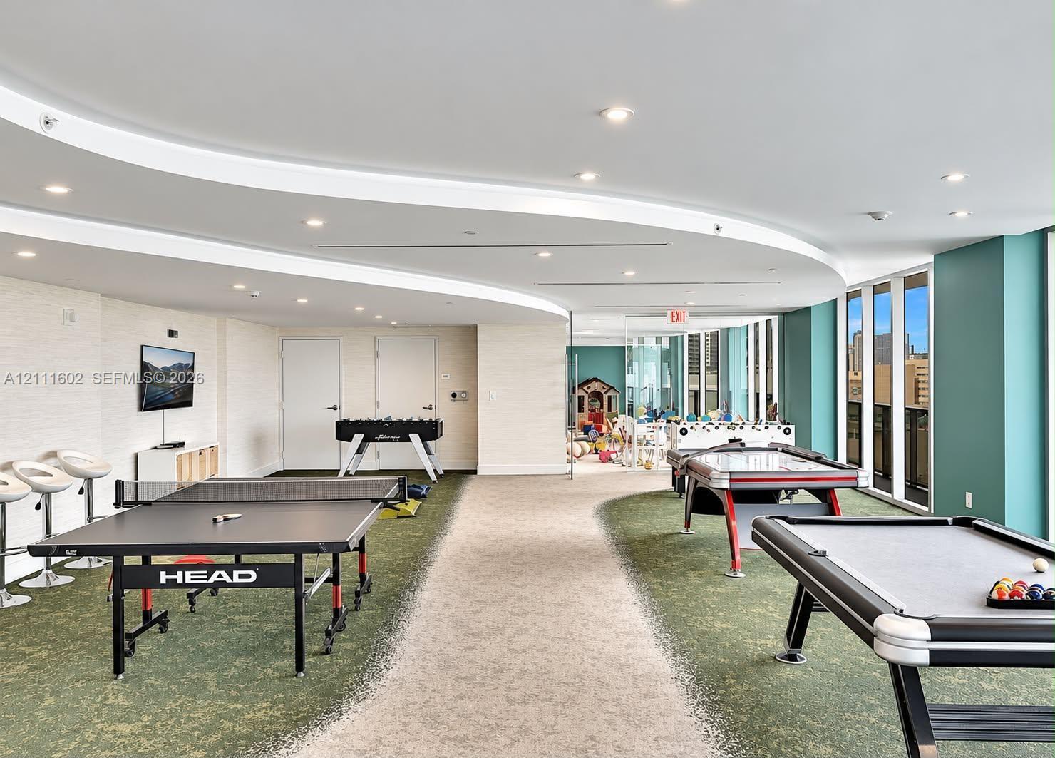 Expansive interior space featuring a curved dropped ceiling, recessed lighting, floor-to-ceiling windows, and dual-textured carpeting