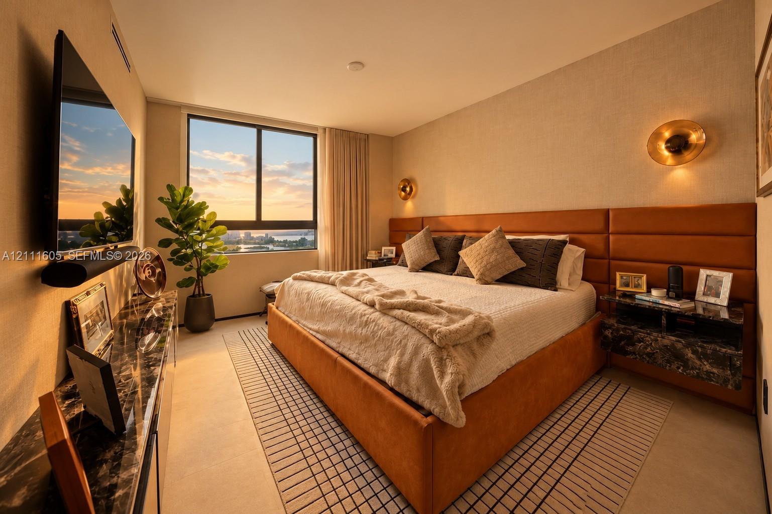 Large-format window, full-height paneled headboard, floating stone-topped nightstands, and metallic circular wall sconces