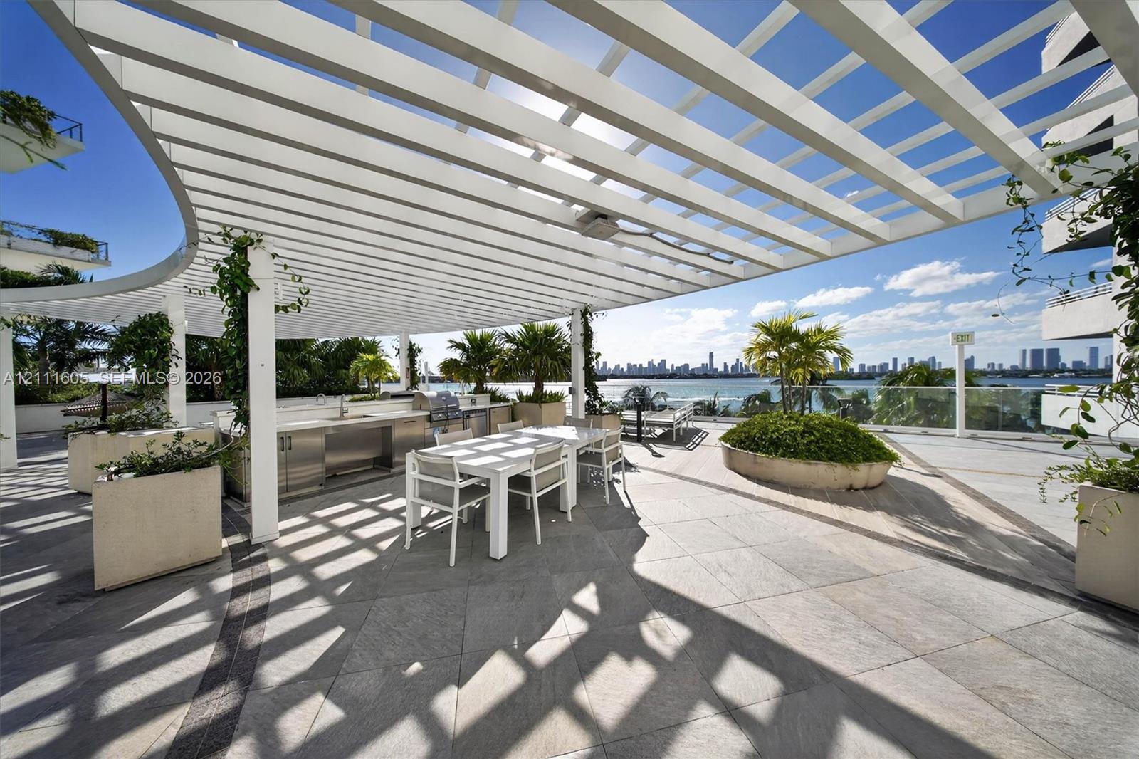High-rise residential tower featuring a white facade, landscaped podium-level terrace, ground-level swimming pool, and water-front placement