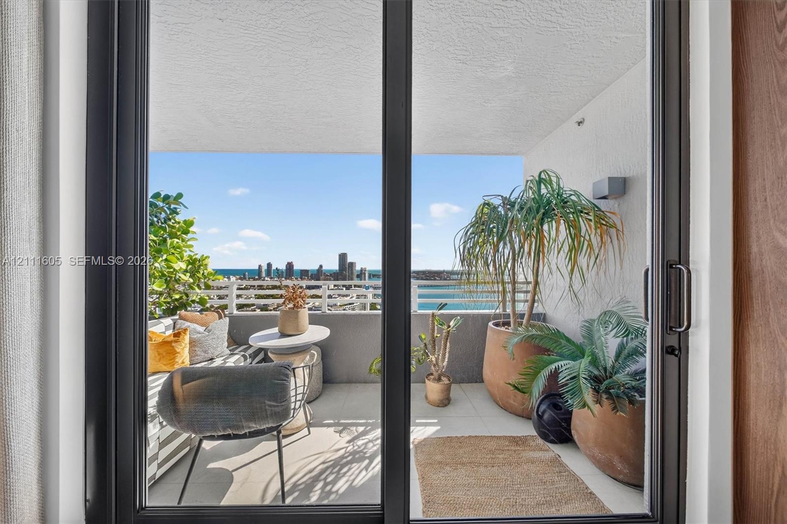 Covered balcony featuring black-framed sliding glass doors, neutral tile flooring, and white metal railings