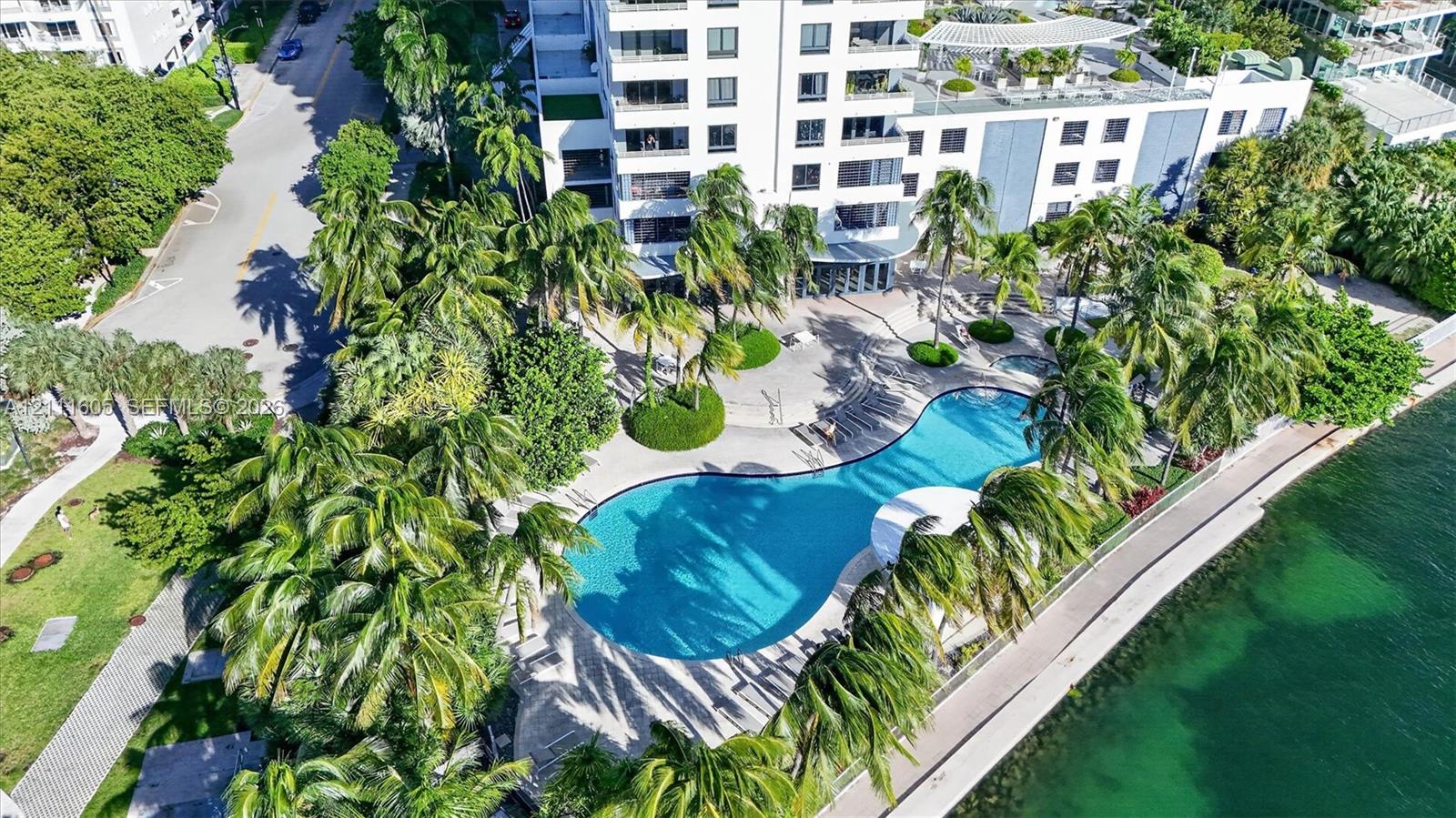 Waterfront property featuring a concrete seawall, stone-paver hardscaping, and a skyline horizon