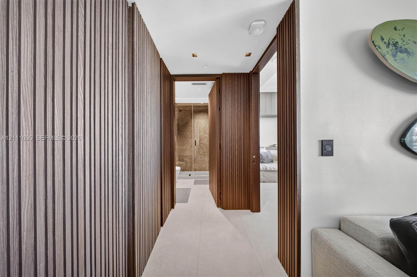 Vertical wood-slat wall paneling, flush-mount ceiling lighting, and large-format tile flooring