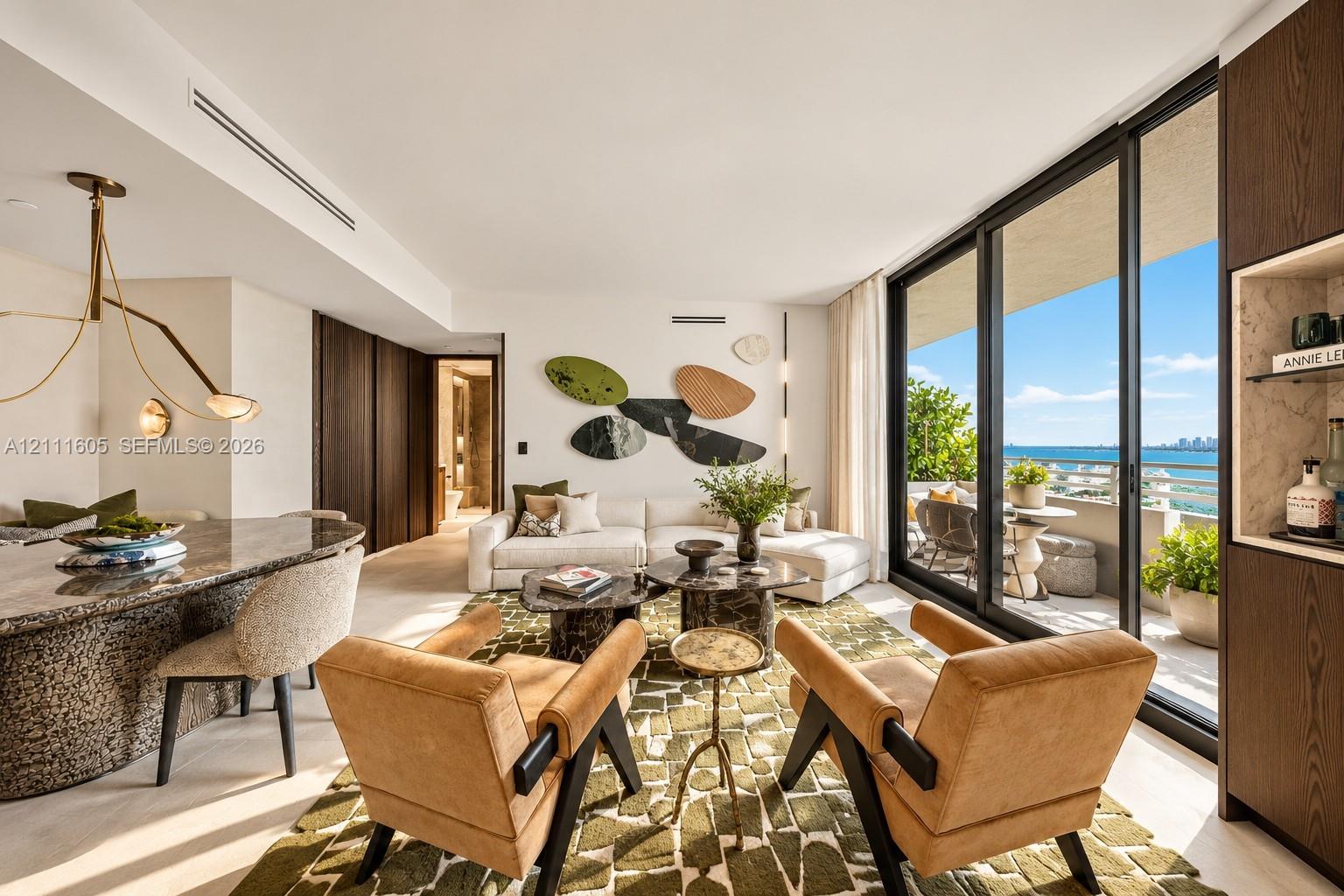 Floor-to-ceiling sliding glass doors, stone-surfaced kitchen island with integrated seating, wood-finish cabinetry, recessed ceiling lighting, and expansive balcony