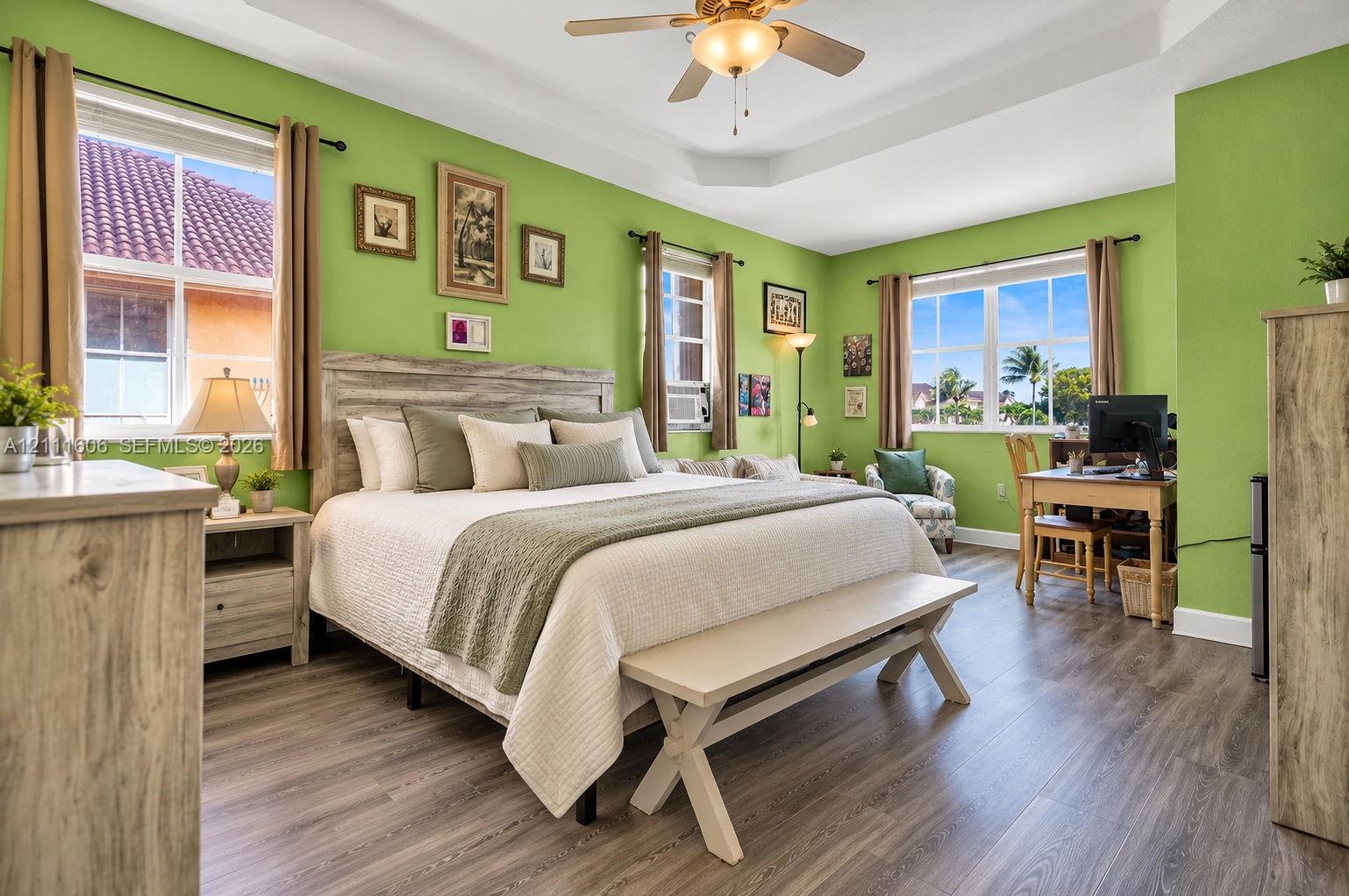 Tray ceiling featuring a central lighted ceiling fan, wood-finish flooring, and multiple large windows Tray ceiling featuring a central lighted ceiling fan, wood-finish flooring, and multiple large windows