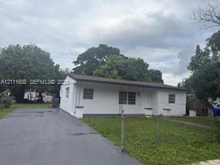 Single-story exterior featuring a white masonry facade, horizontal roofline, long concrete driveway, and front lawn Single-story exterior featuring a white masonry facade, horizontal roofline, long concrete driveway, and front lawn