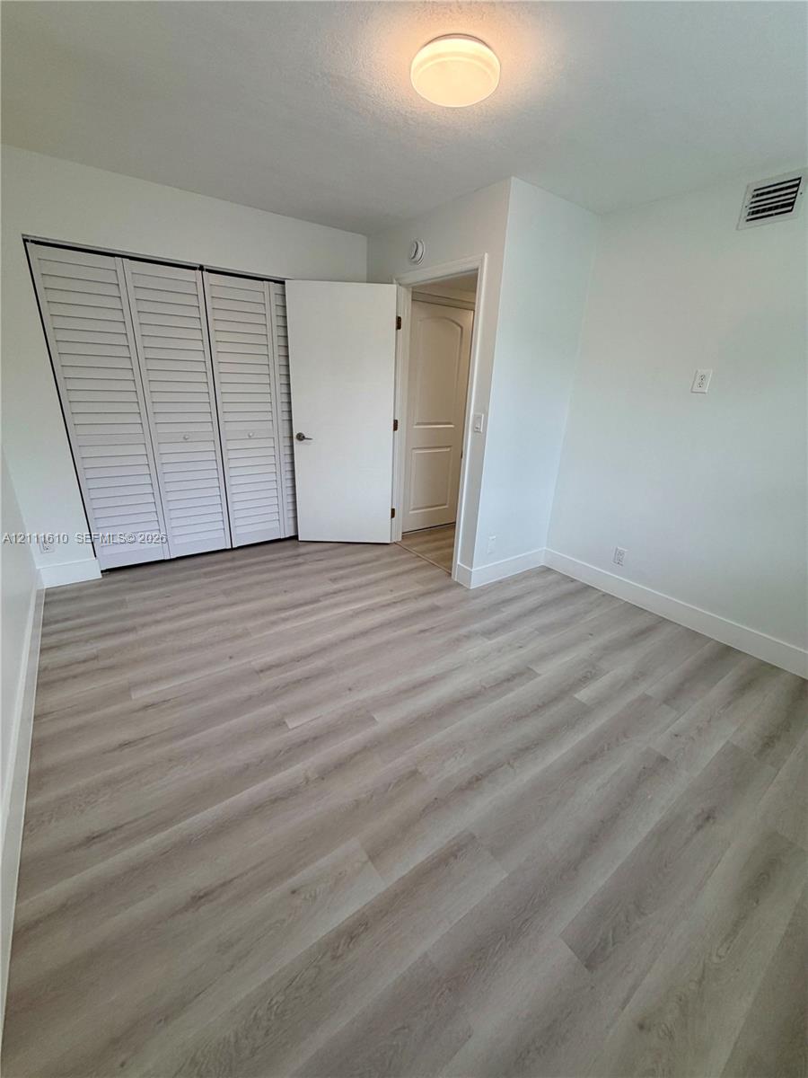 Room featuring light wood-finish flooring, a bi-fold closet door, and a flush-mount ceiling light fixture