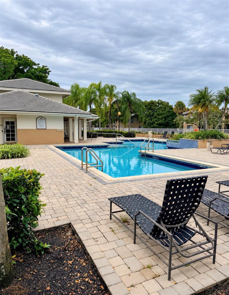 In-ground swimming pool featuring a paver stone deck, metal handrails, and a raised tiled water feature