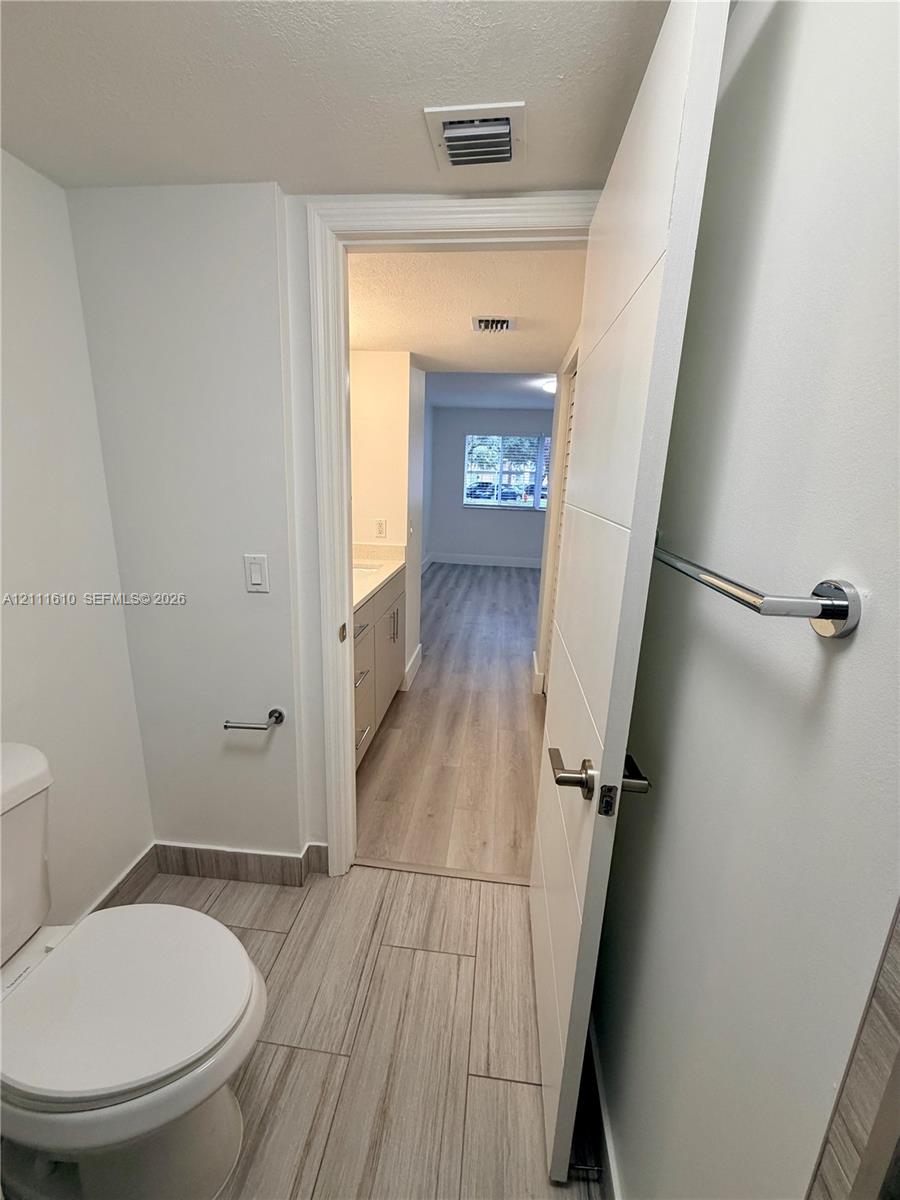 Bathroom featuring light-toned tile flooring, a modern slab-style interior door with a polished chrome handle, and a mounted chrome towel bar