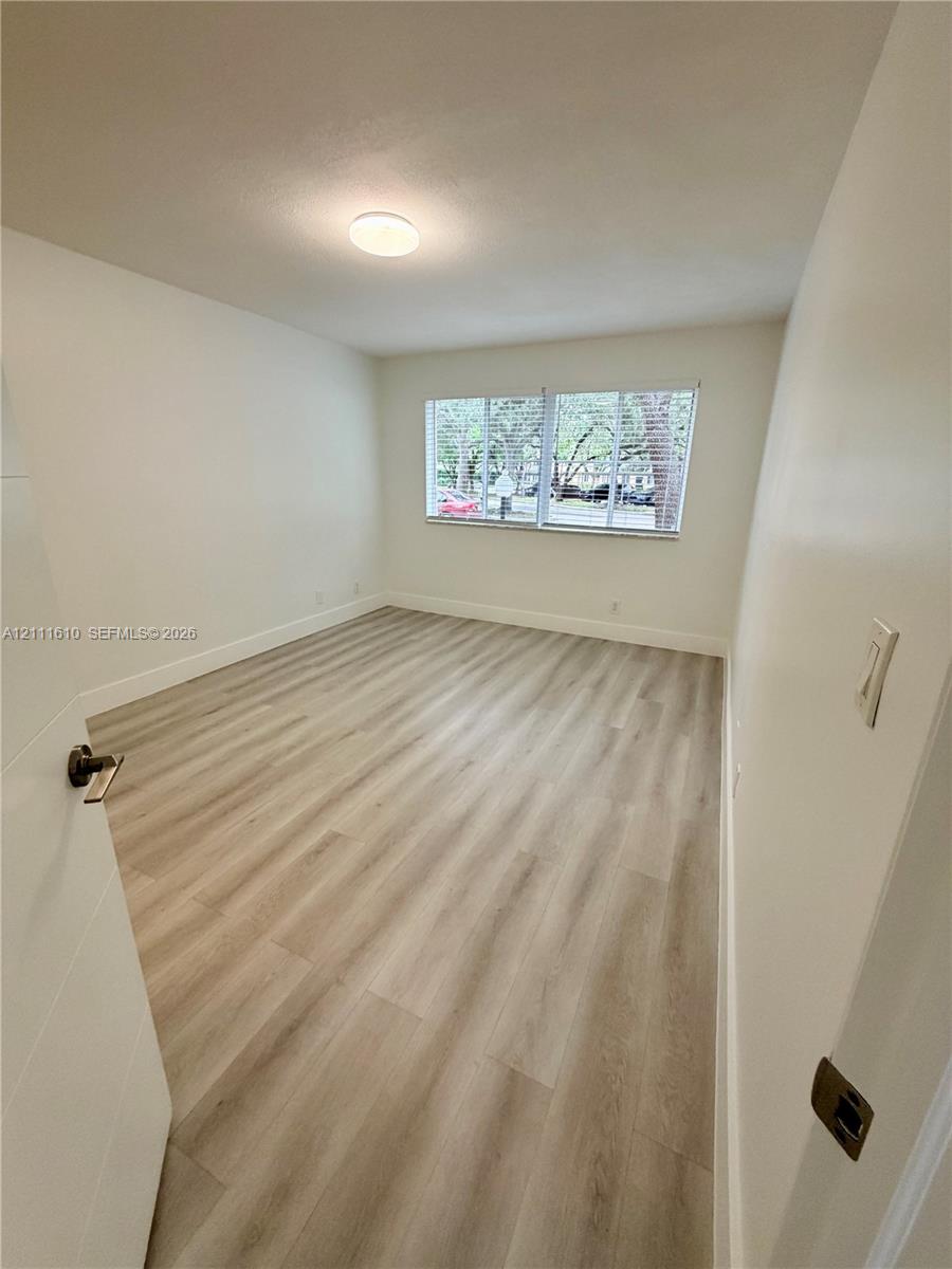 Interior room featuring wood-finish flooring, white walls, and a recessed ceiling light fixture