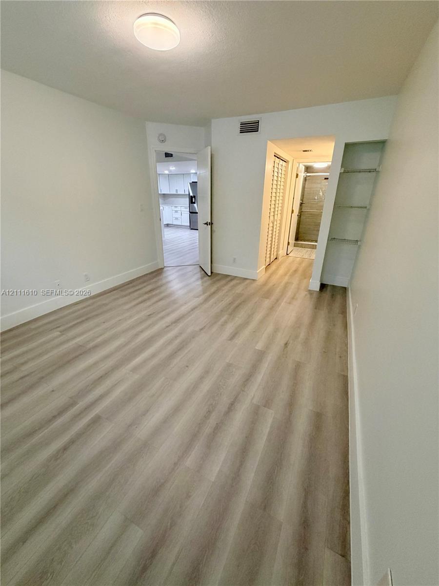 Room featuring wood-finish flooring, recessed flush-mount lighting, built-in open shelving, and a bifold closet door