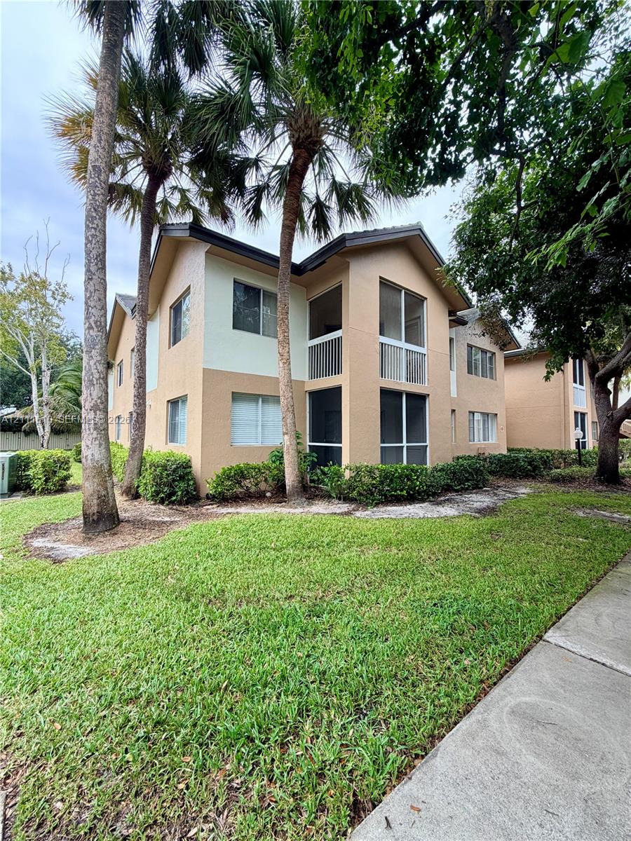 Two-story stucco exterior featuring multi-level screened-in porches, mature palm landscaping, and concrete walkways